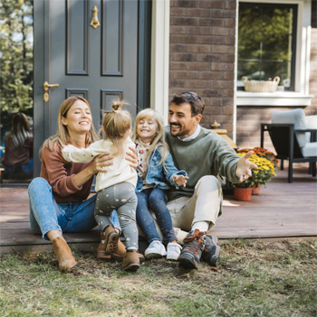 Young parents playing with their daughters on their front porch.