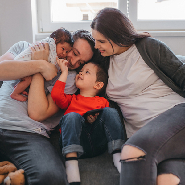 Young family sharing a playful moment with their newborn and young child.